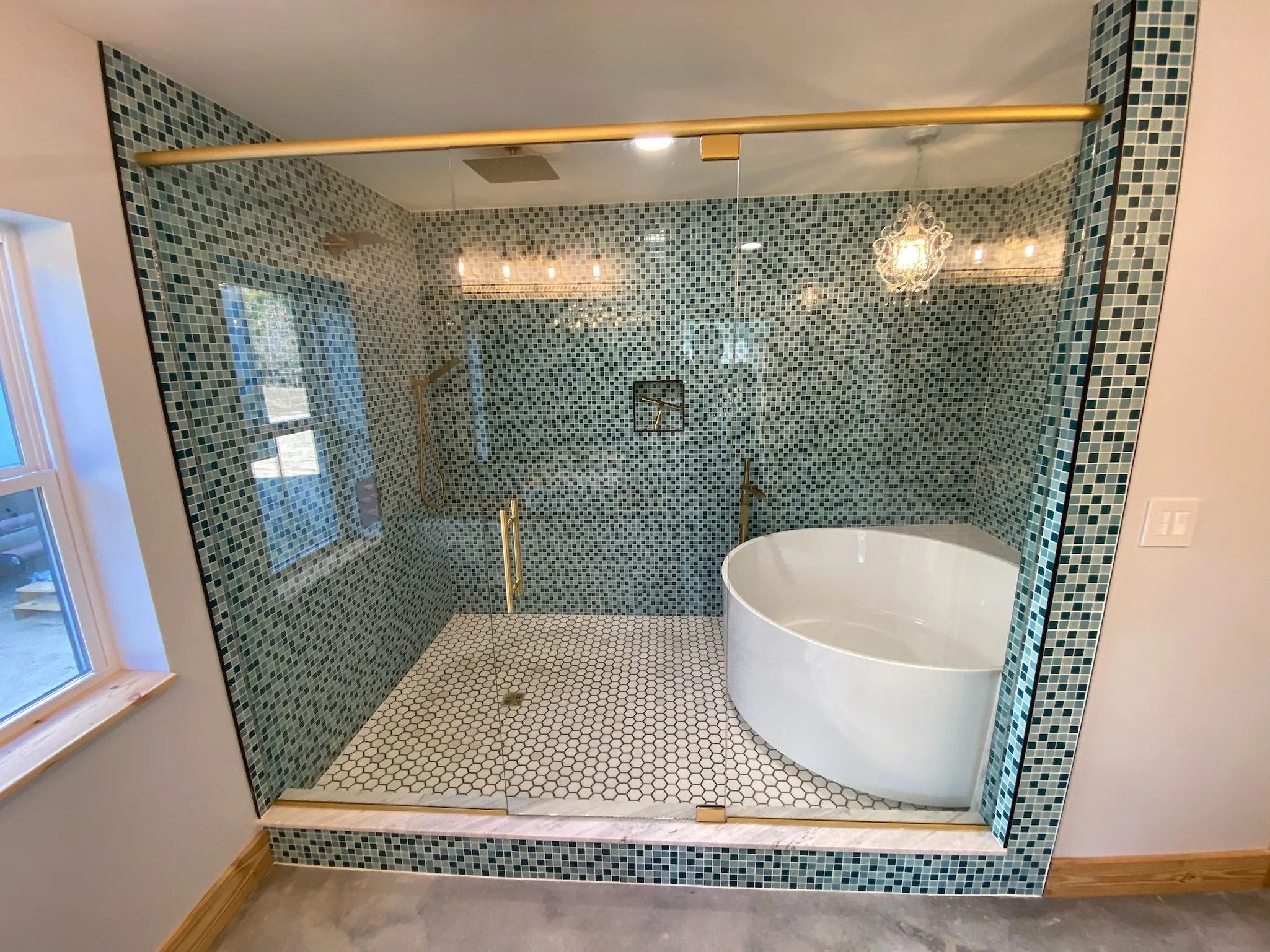 Custom frameless shower glass with brass hardware and tile surround