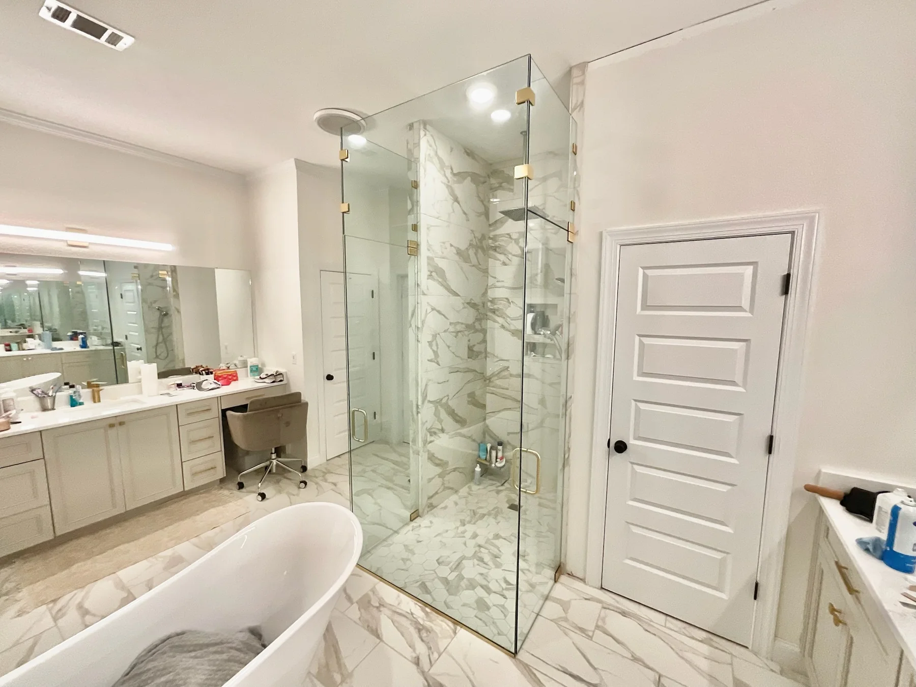 Custom frameless shower glass enclosure with clear panels and brass hardware